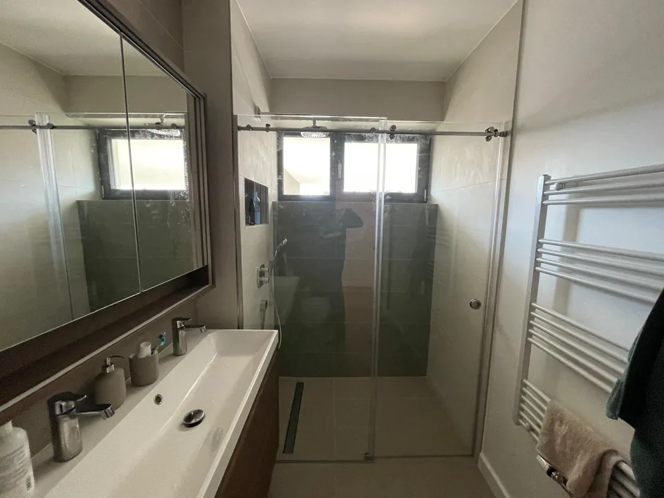 Cabină de duș din sticlă transparentă într-o baie luminoasă.