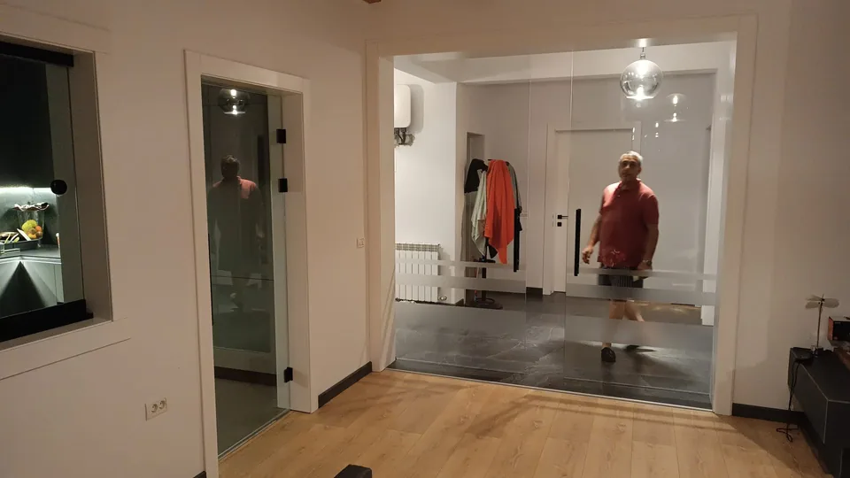Perete de sticlă între living și hol, cu panouri transparente.